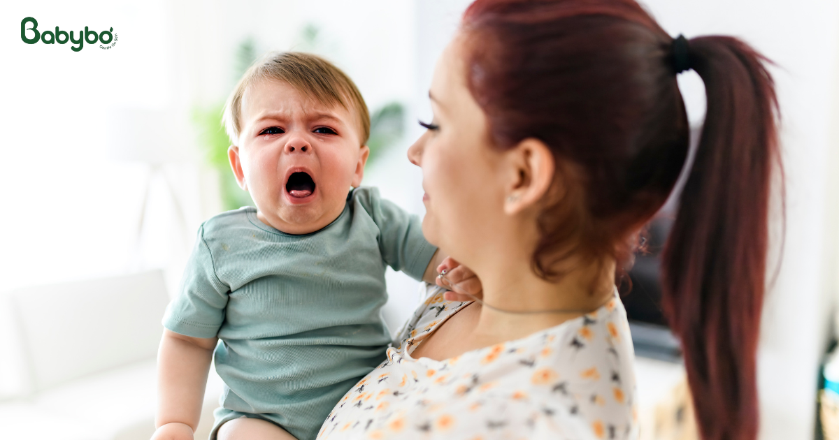 Mẹ bế bé đang quấy khóc, dấu hiệu bé ho về đêm cần được theo dõi.